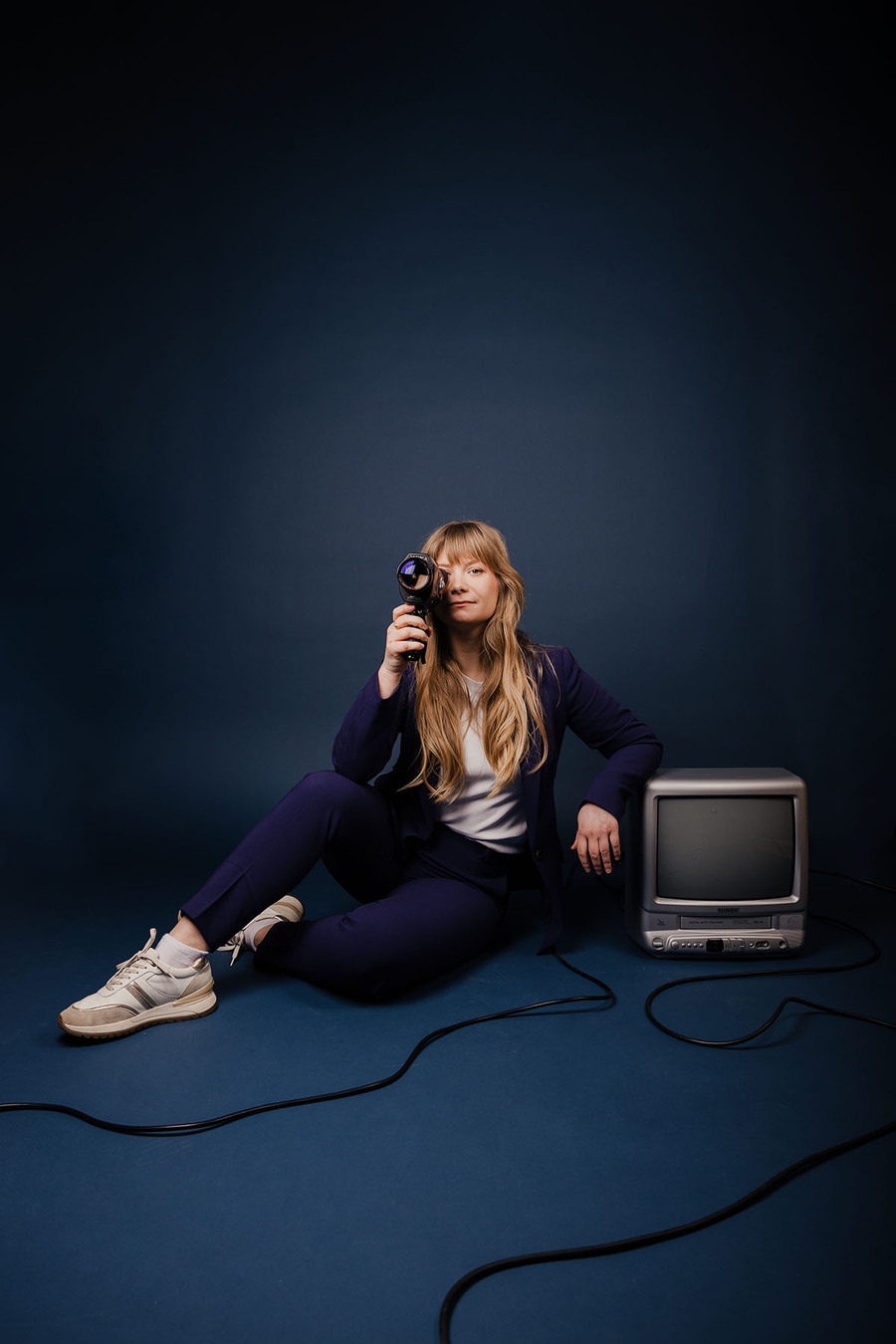 Assise au sol appuyée sur un tv avec un caméscope à la main | © Lucile Dizier